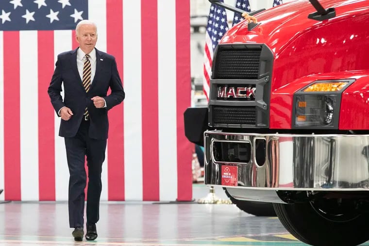 President Joe Biden runs out from behind two Mack trucks before he speaks at the Mack Truck Lehigh Valley Operations in Macungie on Wednesday.