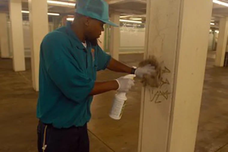 Ranases Philpot , another of the Center City District&#0039;s concourse cleaning crew, scrubs the graffiti off an underground column.