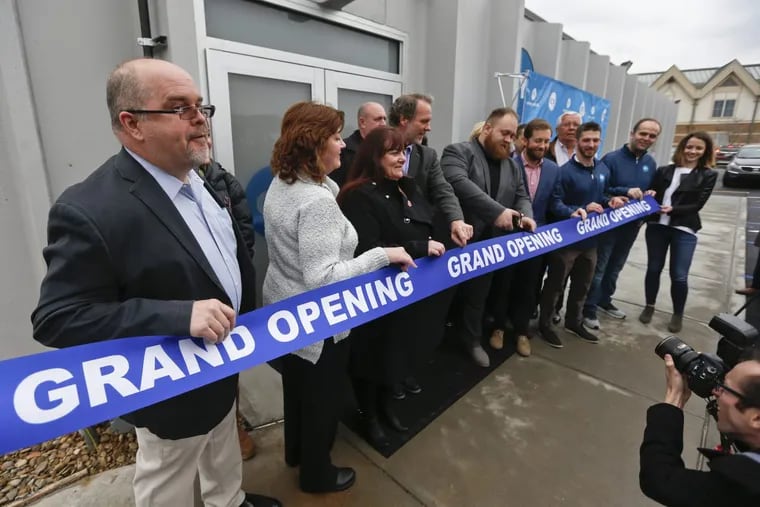 The mayor of Butler, Pa., Ben Smith (center) cuts the ribbon with a group of officials during an open house and media availability for the opening for CY+ Medical marijuana Dispensary last week.