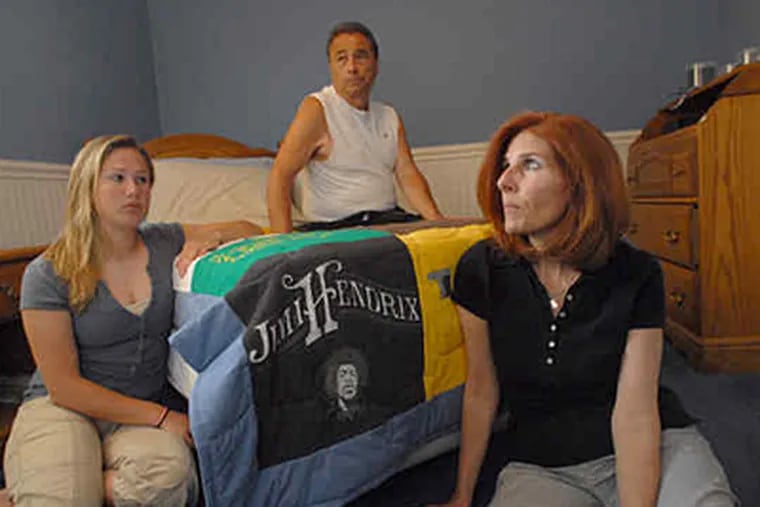 In the Cherry Hill bedroom of suicide victim Jared Bannar are (from left) sister Jordan and parents Michael and Kathy. The quilt was made by Kathy from Jared's T-shirts. (April Saul / Staff)