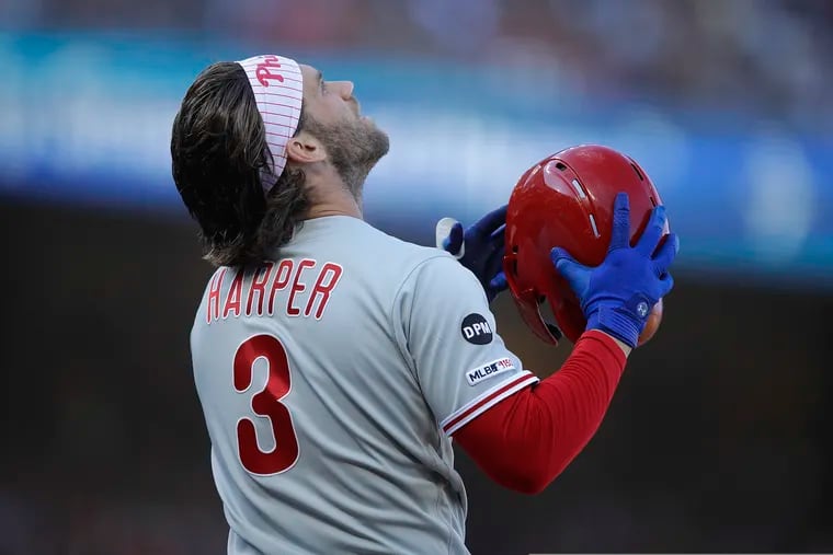 Bryce Harper prepares to put his batting helmet back on in the fourth inning of Sunday's game against the Giants.