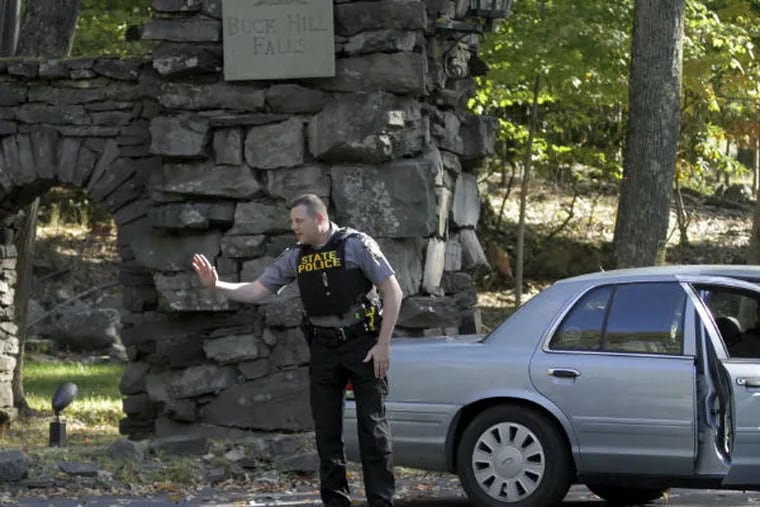 Pennsylvania State Police officers block the entrance to Buck Hill Falls in Barrett Township, Pa, where the search for Eric Frein continues. Frein is suspected of fatally shooting a state trooper and wounding another at the Blooming Grove state police barracks two weeks ago. (AP Photo/Scranton Times & Tribune, Michael J. Mullen)