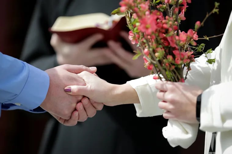 Michael Mountjoy and Allia Dhody hold hands as they get married outside Church of St. Martin-in-the-Fields in the Chestnut Hill neighborhood in Philadelphia in March.