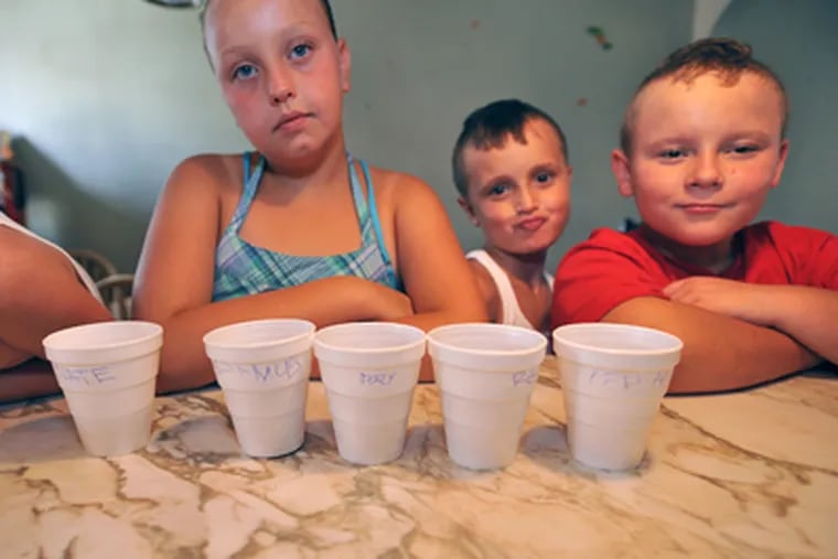 Melissa Scott’s children know the meaning of hunger. Here, they wait to drink juice from their marked cups after being warned there is no more. (Sharon Gekoski-Kimmel / Staff Photographer)