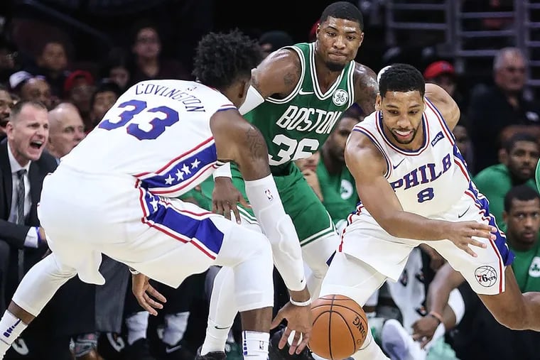 The Sixers’ Robert Covington and Jahlil Okafor try for a loose ball with the Celtics’ Marcus Smart.