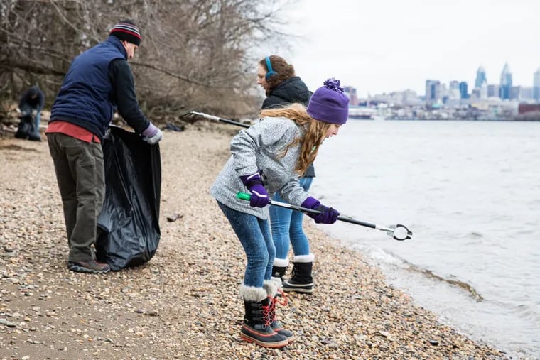 Emma Wenzel (center), 11, picks up trash along the Petty Island shoreline in Pennsauken, N.J., on Saturday morning.