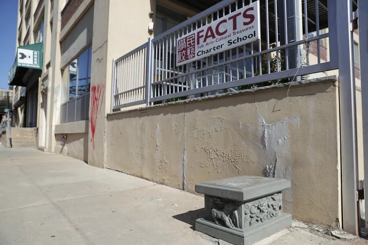 An exterior view of FACTS Charter School in Chinatown North, showing the pedestal where the broken lion statue sat. Its partner remains on post, out of the photo frame, on the other side of the gate.
