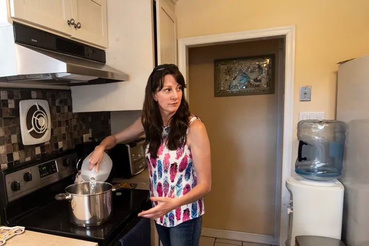 Elizabeth Smith empties a gallon jug of water into the pot she uses to make pasta for her family of four, talking about the water contamination in her Hartsville, Bucks County.