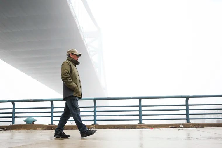 A pedestrian walks underneath a foggy Ben Franklin Bridge in Philadelphia on Wednesday.