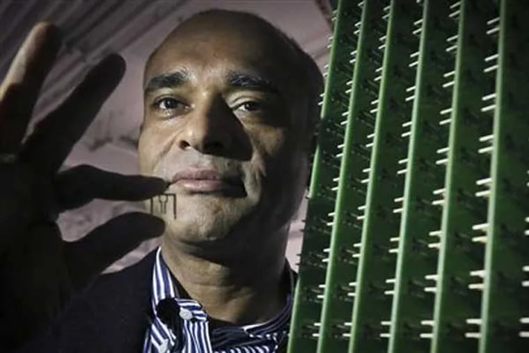 In this Thursday, Dec. 20, 2012, photo, Chet Kanojia, founder and CEO of Aereo, Inc., stands next to a server array of antennas as he holds an antenna between his fingers, in New York.  Aereo is one of several startups created to deliver traditional media over the Internet without licensing agreements. Past efforts have typically been rejected by courts as copyright violations. In Aereo’s case, the judge accepted the company’s legal reasoning, but with reluctance. (AP Photo/Bebeto Matthews)