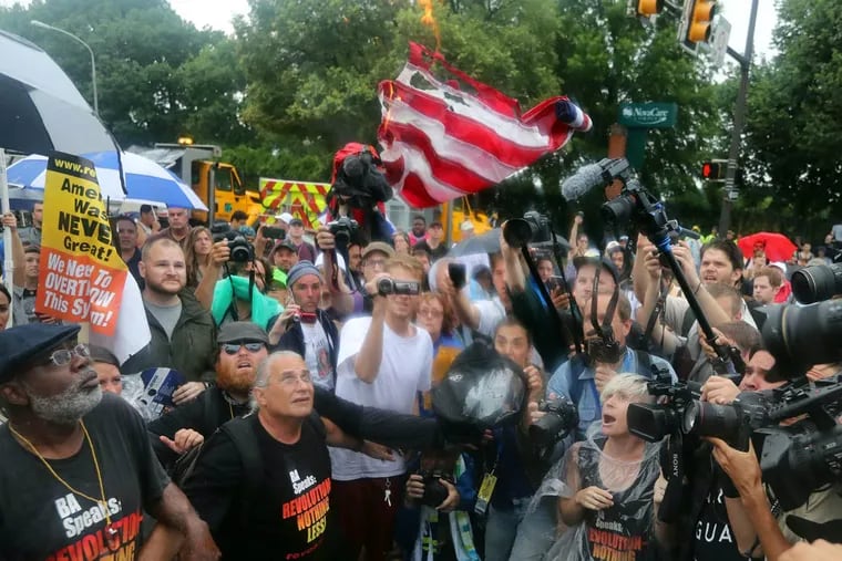 Protesters attempt - unsuccessfully - to burn an American flag outside the Wells Fargo Center. In all, hundreds of protesters turned out, advocating a variety of causes even as severe thunderstorms rumbled into the city.