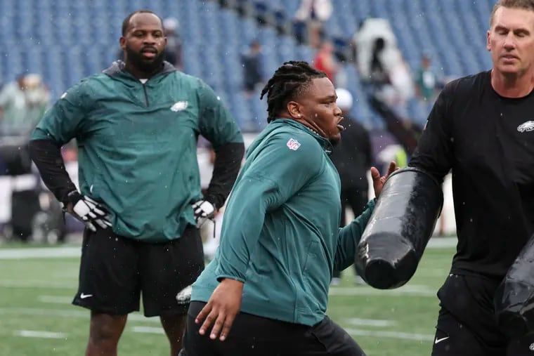 Eagles defensive tackle Jalen Carter warms up with Fletcher Cox watching nearby before the game against New England Patriots on Sept. 10.