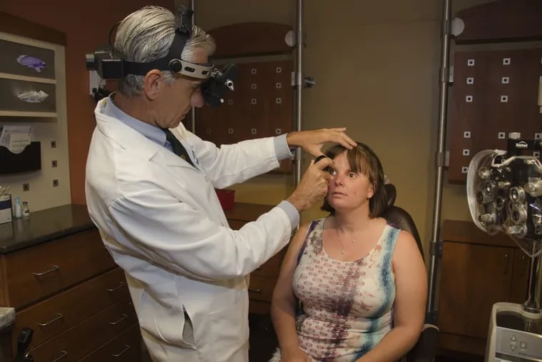 University of Pennsylvania eye surgeon Albert Maguire examines Stacy Young, who lost her left eye and became legally blind in her right eye from a fireworks injury in 2000.
