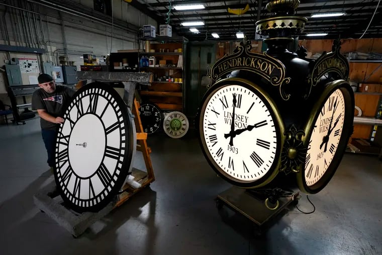 Dan LaMoore rolls a tower clock face across the plant floor at Electric Time Company on Friday in Medfield, Mass. Daylight saving time ends at 2 a.m. Sunday.