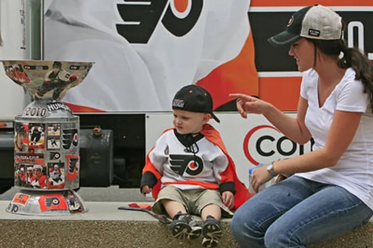 Brenna Philpott (right) from Haddon Twp, NJ, points to a homemade Stanley Cup to her nephew Sam D'Antonio, 17 mo. from Deptford, As fans wait, food experts debate which city has the best cuisine. (Akira Suwa / Staff Photographer )