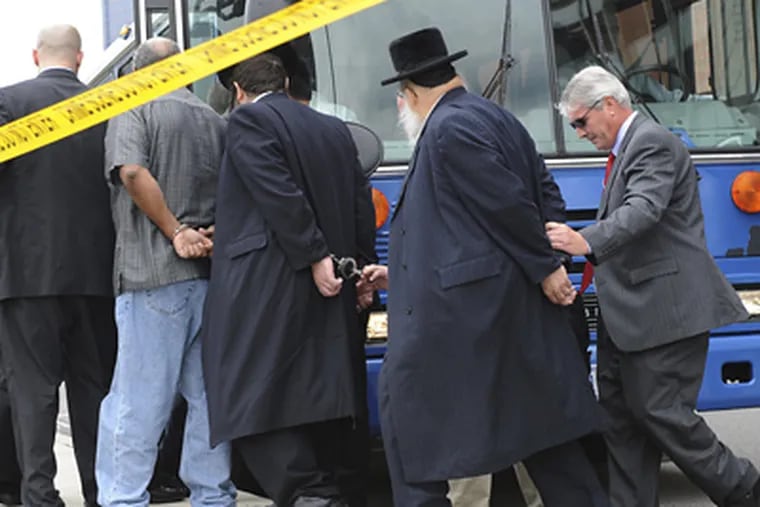 FBI agents escort some of the 44 people arrested yesterday from the agency’s office in Newark, N.J. Among those charged were a number of rabbis. (Louis Lanzano / Associated Press)