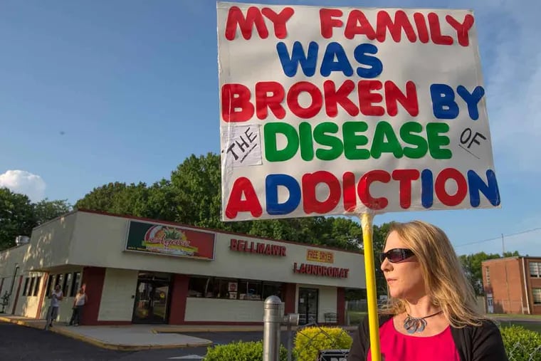 Linda Griffith stands in a vigil for drug awareness several weeks after drug busts at Johnnies Liquors, a Bellmawr liquor store, and Bellmawr Laundromat, the property in the background.