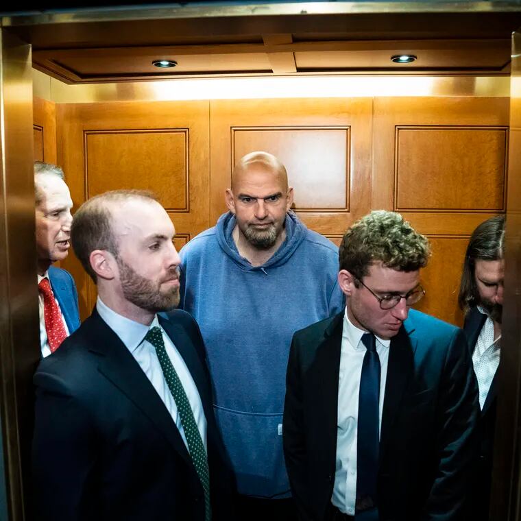 A sweatshirt-wearing Sen. John Fetterman (D., Pa.) is surrounded by suits at the Capitol building.