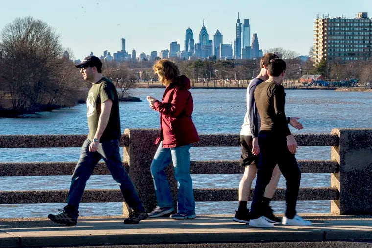 Walkers take in both the river and Philadelphia skyline views as they cross a bridge over the Cooper River on an unseasonably warm day in January.