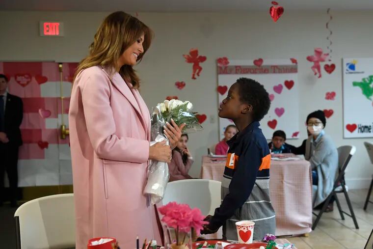 First lady Melania Trump is presented with a bouquet of flowers from Amani, 13, of Mombasa, Kenya, during her visit to the National Institutes of Health to see children at the Children's Inn in Bethesda, Md., Thursday, Feb. 14, 2019, and celebrate Valentine's Day.