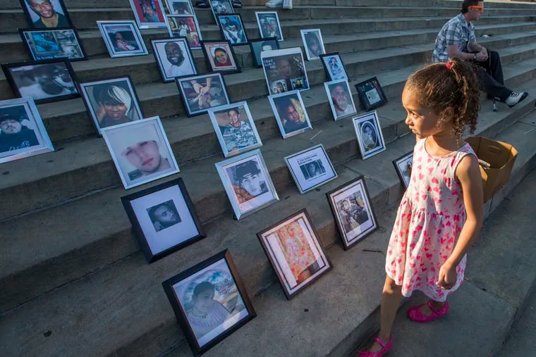 Elisha Sharpe walks by photos of the victims of gun violence placed on the Art Museum steps in June 2017.