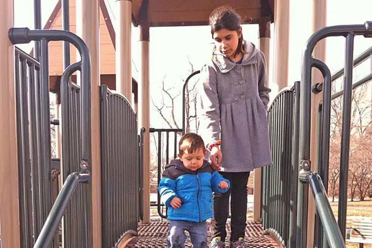 Logan Giammarco, 1, explores a bridge under the watchful eye of his sister Dakota, 10, on Sunday at Pleasant Hill Playground in Torresdale, where an arsonist torched swings and other play equipment. (Photo by Dan Geringer/Daily News Staff)