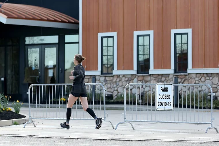 A jogger passes a park closure sign at Cooper River Park in Pennsauken, N.J., on April 8, 2020. Gov. Phil Murphy announced that all county parks will close indefinitely beginning at 8 p.m. on April 7 due to the coronavirus outbreak.