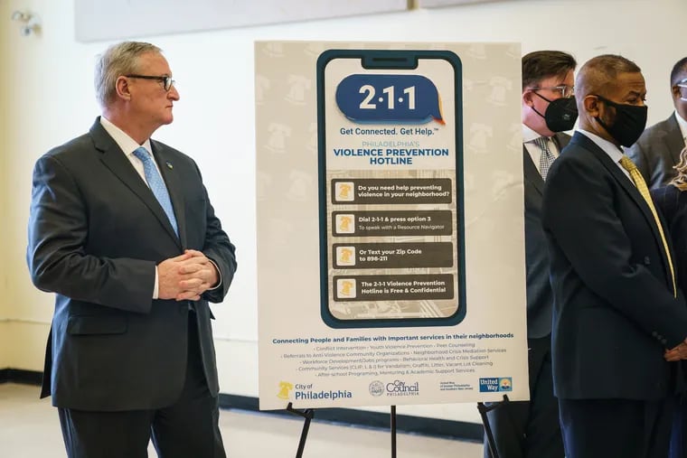 Mayor Jim Kenney stands next to a sign with information about the new 211 violence prevention hotline.