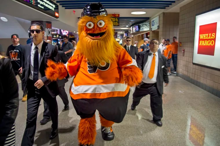 Gritty, the Philadelphia Flyers' new mascot, travels with his "security detail" through the crowd during a game at the team's home opener at the Wells Fargo Center on Oct. 9, 2018.