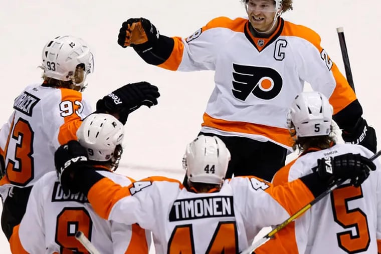 Claude Giroux (28) smiles as he arrives to join the celebration of a goal by Jakub Voracek (93), of the Czech Republic, against the Phoenix Coyotes, with teammates Braydon Coburn (5), Kimmo Timonen (44), of Finland, and Steve Downie (9) during the third period of an NHL hockey game Saturday, Jan. 4, 2014, in Glendale, Ariz. The Flyers defeated the Coyotes 5-3. (Ross D. Franklin/AP)