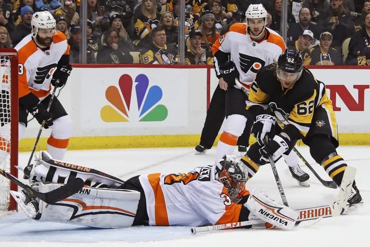 Philadelphia Flyers goaltender Petr Mrazek (34) dives to cover the puck before Pittsburgh Penguins' Carl Hagelin (62) can get his stick on it during the second period of an NHL hockey game in Pittsburgh, Sunday, March 25, 2018.