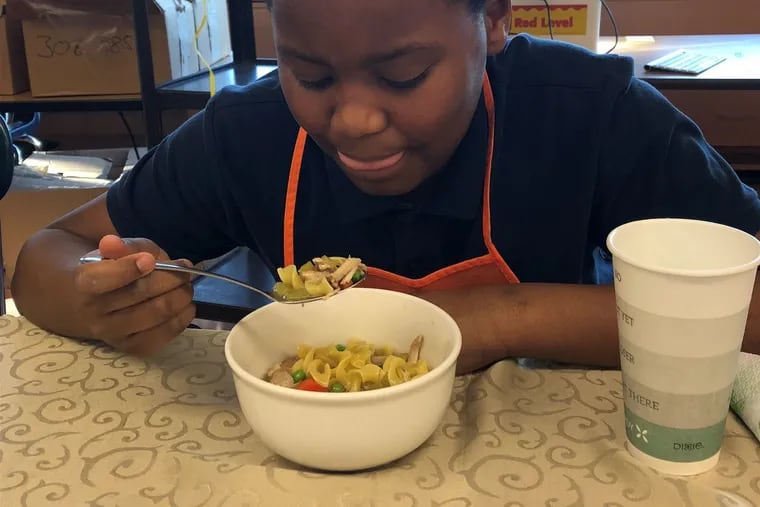 Omar Drinkard enjoys his first taste of the chicken noodle soup that he and other students learned to make during week 2 of the spring 2019 My Daughter's Kitchen cooking program at Wiggins School.