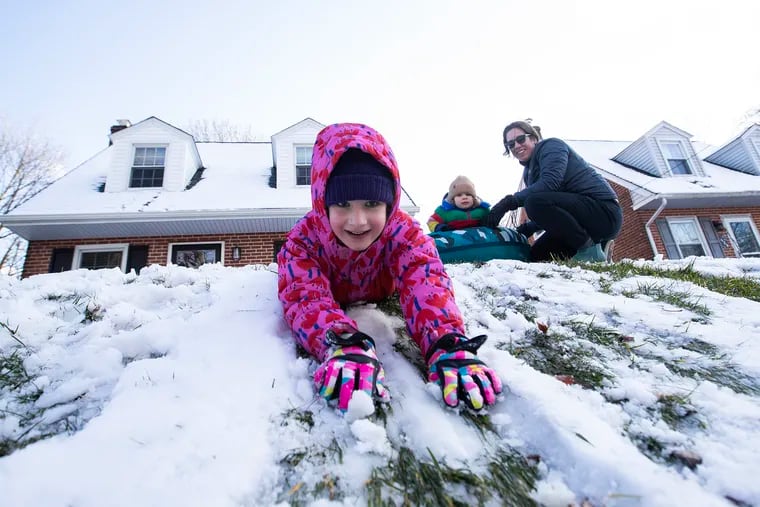 Etta Rochon, 6, does some body sledding down the hill in their front yard. Her mother, Britt Rochon, and sister Lola, 1, are above in their yard in Media on Tuesday.