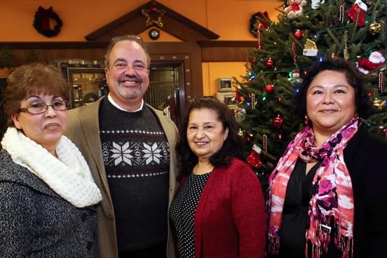 Juan Guerra, second from left, executive director of the ACLAMO Family Center, poses with staff members (from left) Margarita Contreras, Reina Guevara and Maricruz Clemens during their office holiday party in Norristown on Tuesday, Dec. 23, 2014. (For the Inquirer/Joseph Kaczmarek)