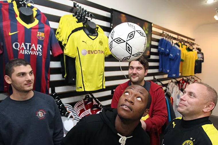 The Media Football Club will be opening on W. State Street in Media  on Nov. 30, 2013.  (Left to right) Domenick Cucinotta and Ebun Olaloye, both of Live Breathe Futbol, store manager Johnny Dickerson (in back), and owner Tom Kennedy are show in the soccer store specialty store on Nov. 26, 2013.  ( CHARLES FOX / Staff Photographer )