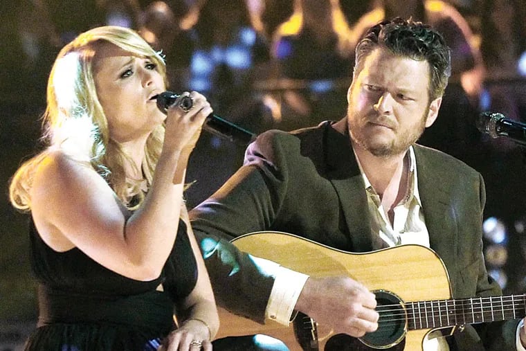 This May 21, 2013 photo released by NBC shows married singers Miranda Lambert, left, and  Blake Shelton performing an acoustic version of the hit "Over You" during a broadcast of the singing competition series, "The Voice," in Los Angeles. Shelton and NBC are putting together a benefit for Oklahoma tornado victims. Shelton, an Oklahoma native, told reporters about the fundraising effort after Tuesday night's episode of "The Voice." He said the benefit would be held soon in nearby Oklahoma City.  (AP Photo/NBC, Trae Patton)