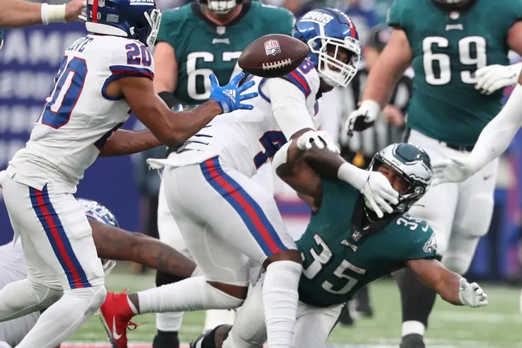 New York Giants cornerback Julian Love (left) grabs the ball after Philadelphia Eagles running back Boston Scott (right) fumbles in the fourth quarter. The Eagles lose 13-7 to the Giants at MetLife Stadium in East Rutherford, New Jersey on Sunday, Nov. 28, 2021.