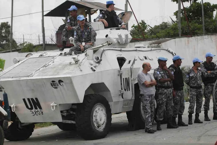 United Nations peacekeeping forces wait outside U.N. headquarters Monday in Abidjan, Ivory Coast. A Security Council resolution extends the force's mandate in the country to June 30.