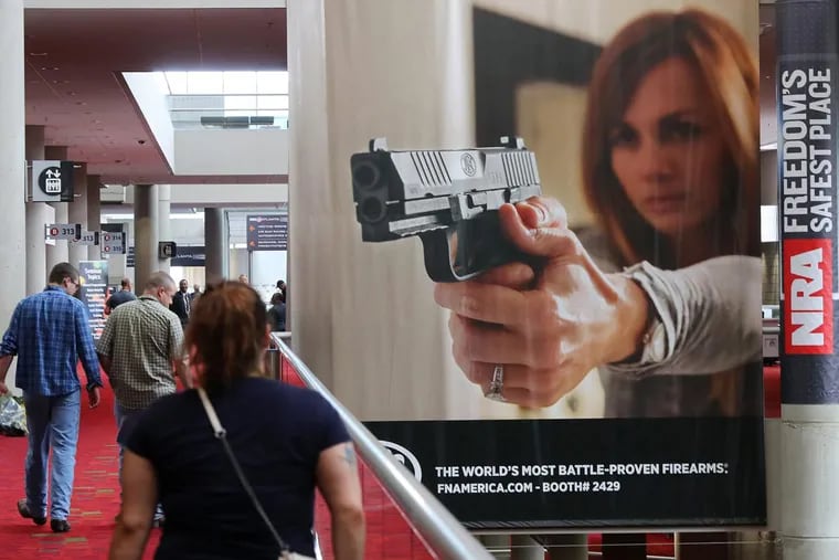 Attendees pass by a large banner advertising a handgun during the NRA convention at the Georgia World Congress Center on  April 27, 2017, in Atlanta,