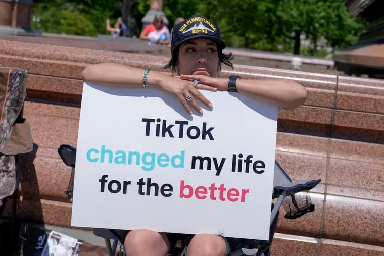 A TikTok content creator sits outside the U.S. Capitol on Tuesday. TikTok is gearing up for a legal fight against a U.S. law that would force the social media platform to break ties with its China-based parent company or face a ban.