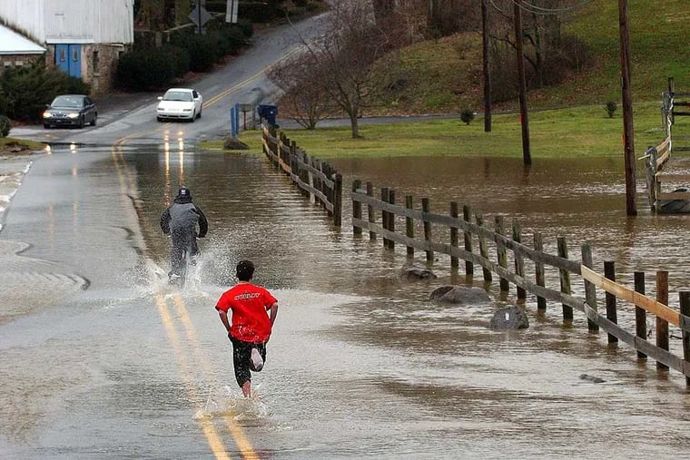 File photo; Alex Sarcione (red shirt), age 13, and his friend Ryan Carrone (on bike) age 13, race across the flooded portion of the East Branch of the Brandywine Creek, running and riding where many cars did not dare to drive.