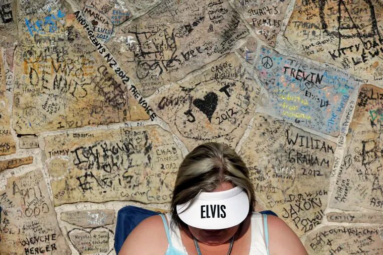 Elvis Presley fan Adrian Cornelius, of Coleman, Ala., waits in line at the graffiti-covered wall in front of Graceland, Presley's Memphis home, on Wednesday, Aug. 15, 2012, in Memphis, Tenn. Presley fans from around the world are at Graceland to take part in the annual candlelight vigil marking the 35th anniversary of his death. (AP Photo/Mark Humphrey)