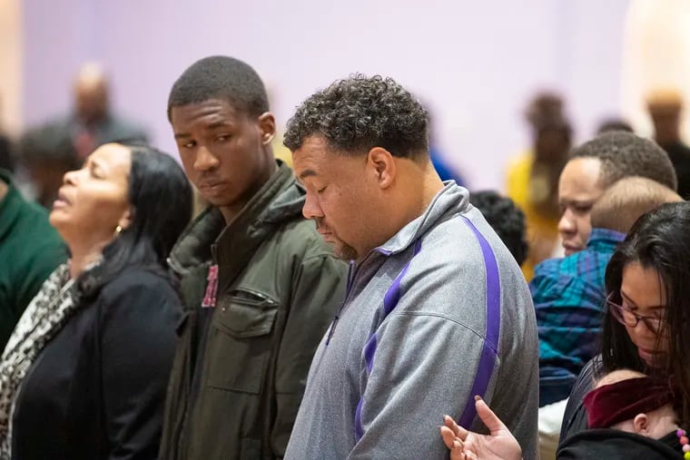Camden High School head football coach Dwayne Savage (center) prays during a service at the First Nazarene Baptist Church in Camden Sunday. He would not comment on the shooting Friday night during his team's playoff game against Pleasantville High School.