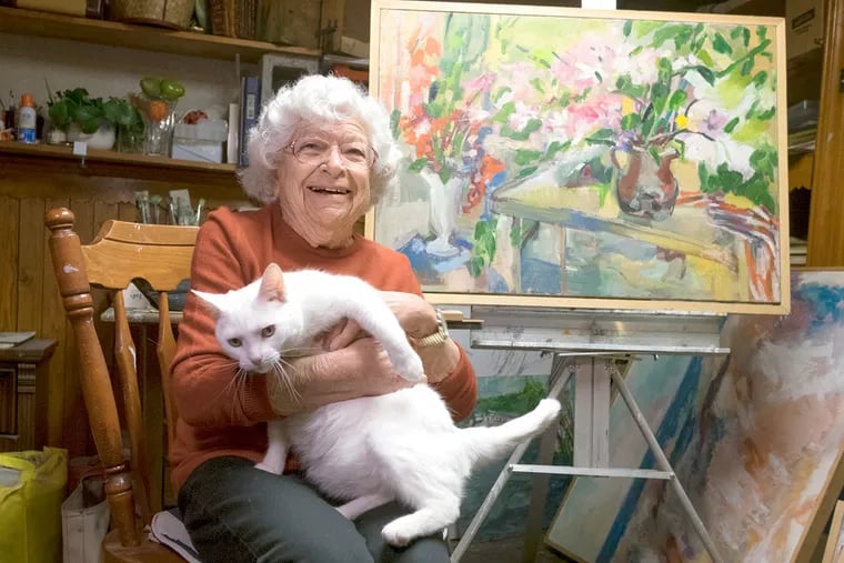 In her Overbrook studio, Bernice Paul with Kitty. The University City Arts League will show her works through April.