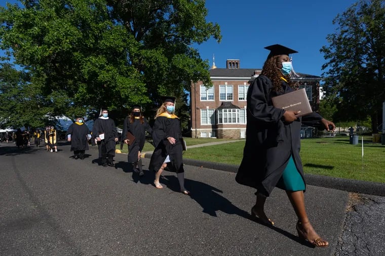 Geralda Saint Jean, right, front walks across campus with classmates at the end of the graduation ceremony at Rowan University's Glassboro campus.