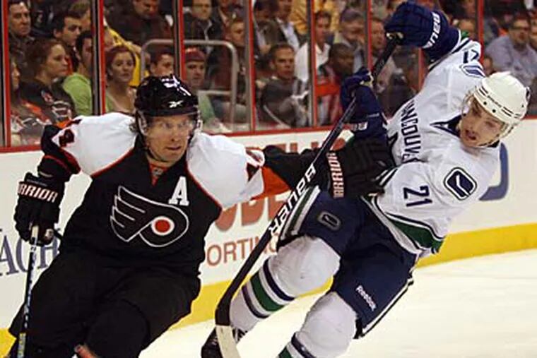 Flyers' Kimmo Timonen controls the puck against Vancouver Canucks' Mason Raymond during the first period on Thursday, December 3, 2009.  (Yong Kim / Staff Photographer)