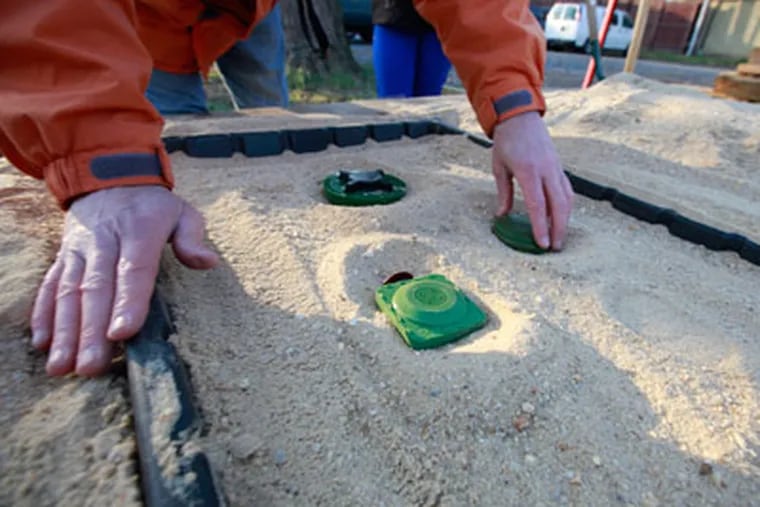 Tim Bechtel plants a model mine in a sand box for a demonstration how his system can locate the device. (  DAVID SWANSON / Staff Photographer )