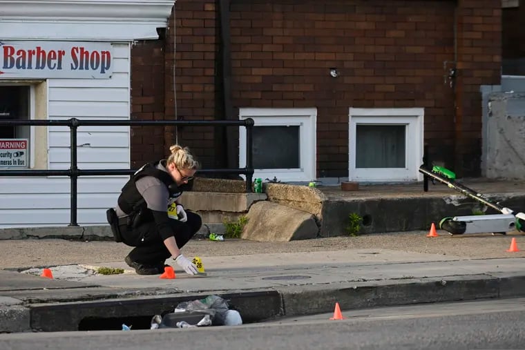 A Baltimore police forensics officer places an evidence marker next to a bullet casing while investigating the scene of a shooting in Baltimore on Sunday, April 28, 2019. A gunman fired indiscriminately into a crowd that had gathered for Sunday afternoon cookouts along a west Baltimore street, killing at least one person and wounding several others, authorities said.