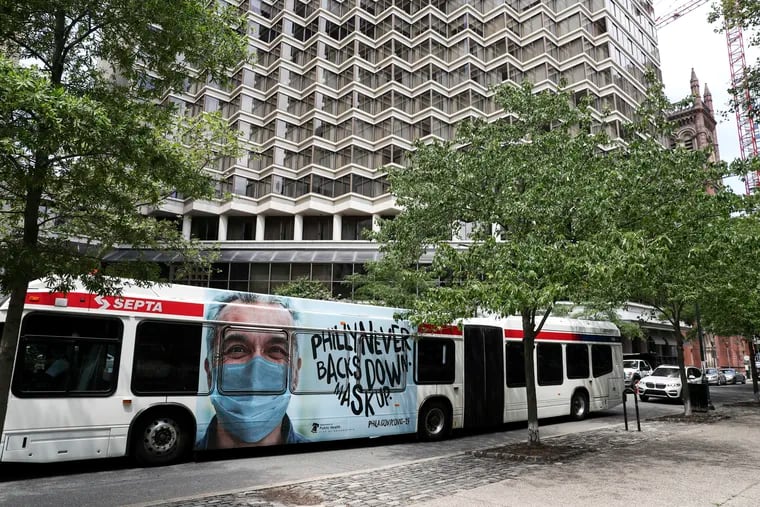 A SEPTA bus displays one of the city's new ads promoting mask-wearing. It reads, "Philly never backs down; mask up." As it goes down the street on Monday, in the background is the Rittenhouse Hotel, where the Miami Marlins were believed to be quarantining since their Sunday game against the Phillies.