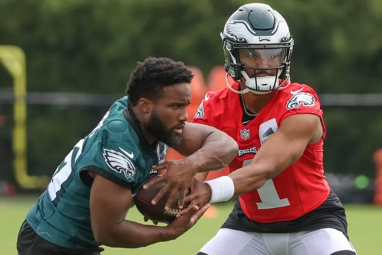 Eagles quarterback Jalen Hurts hands off to running back Boston Scott during a training-camp practice.